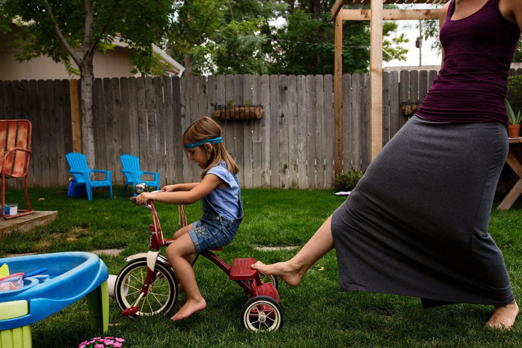 Little girl in headband on trike in backyard