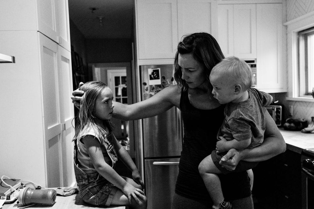 Mom soothing daughter and holding baby