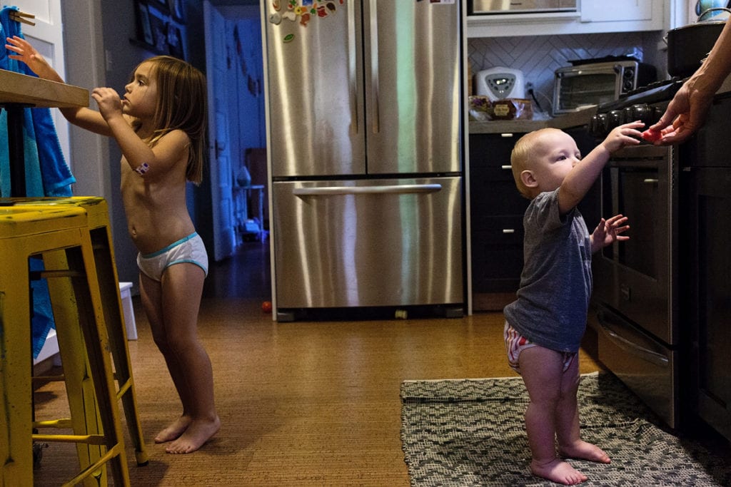 Baby and sister in underwear in kitchen
