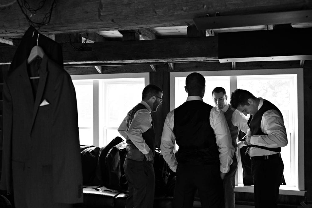 Groom and wedding party getting ready in rustic log beam room