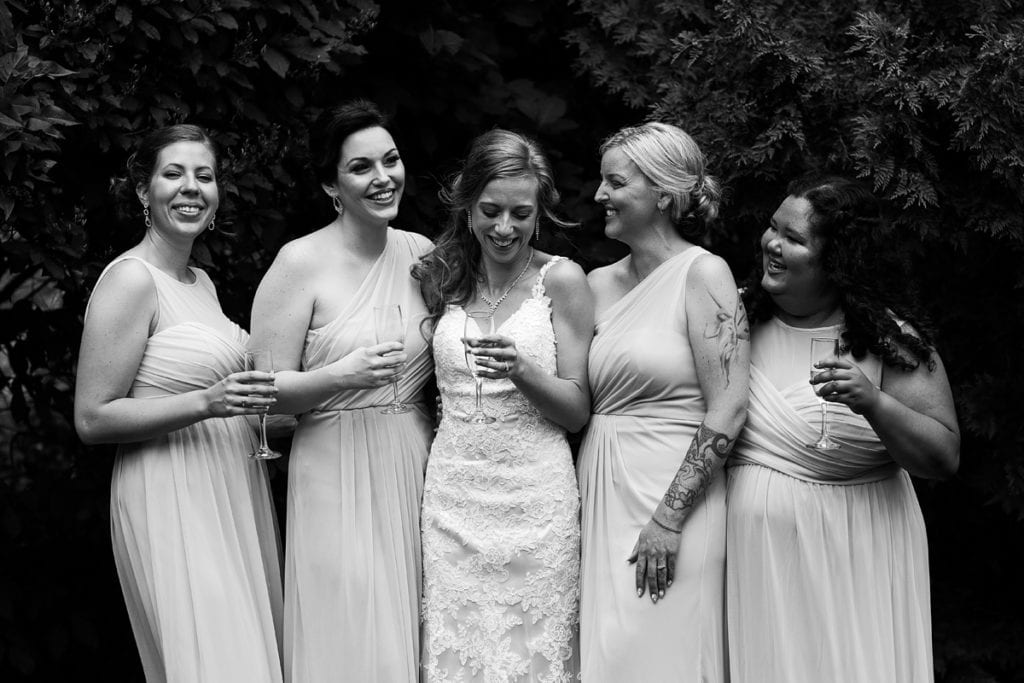 Bride with attendants sharing glass of champagne