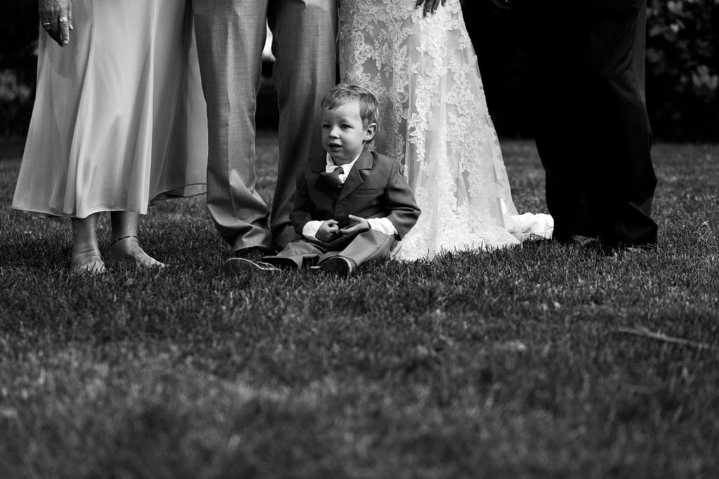 Ring bearer sitting at feet of wedding party