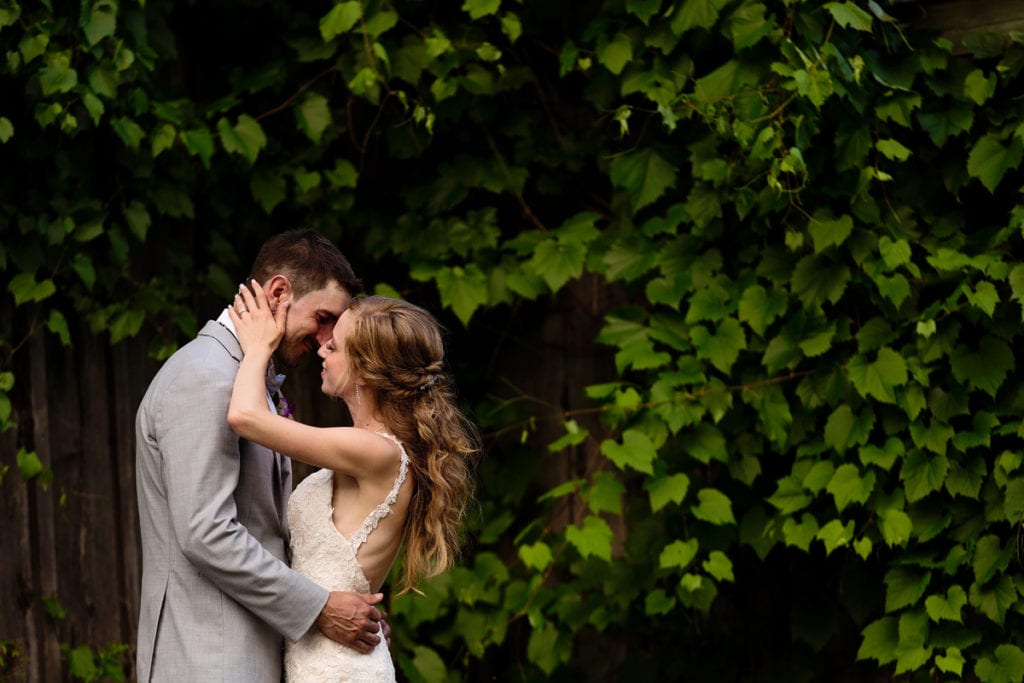 Bride and groom kissing in patch of lush greenery at Strathmere wedding