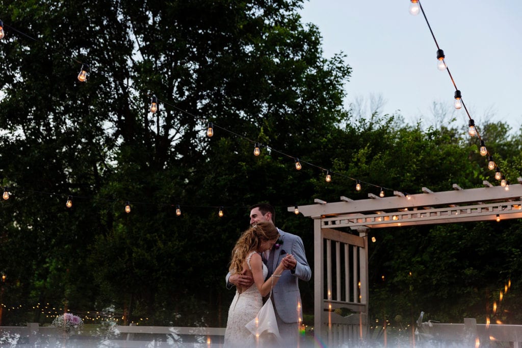 Bride and groom dancing under string lights on patio at intimate Strathmere wedding