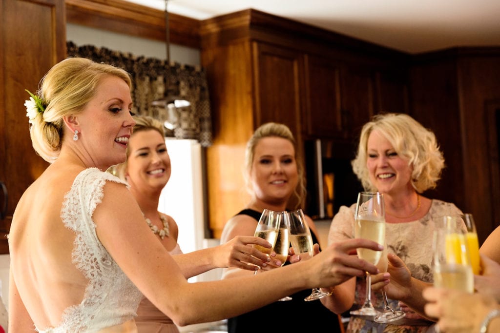 bride and attendants toasting with champagne in family kitchen