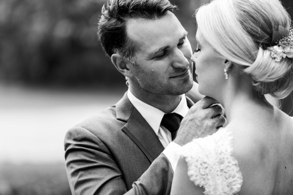Groom gently touching bride's face in rural backyard wedding