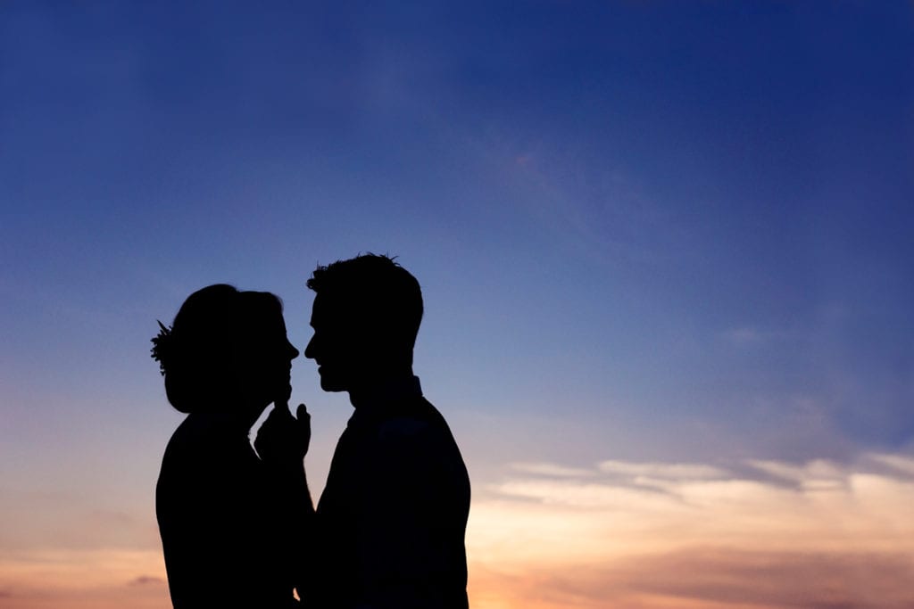Silhouette of bride and groom against summer sunset