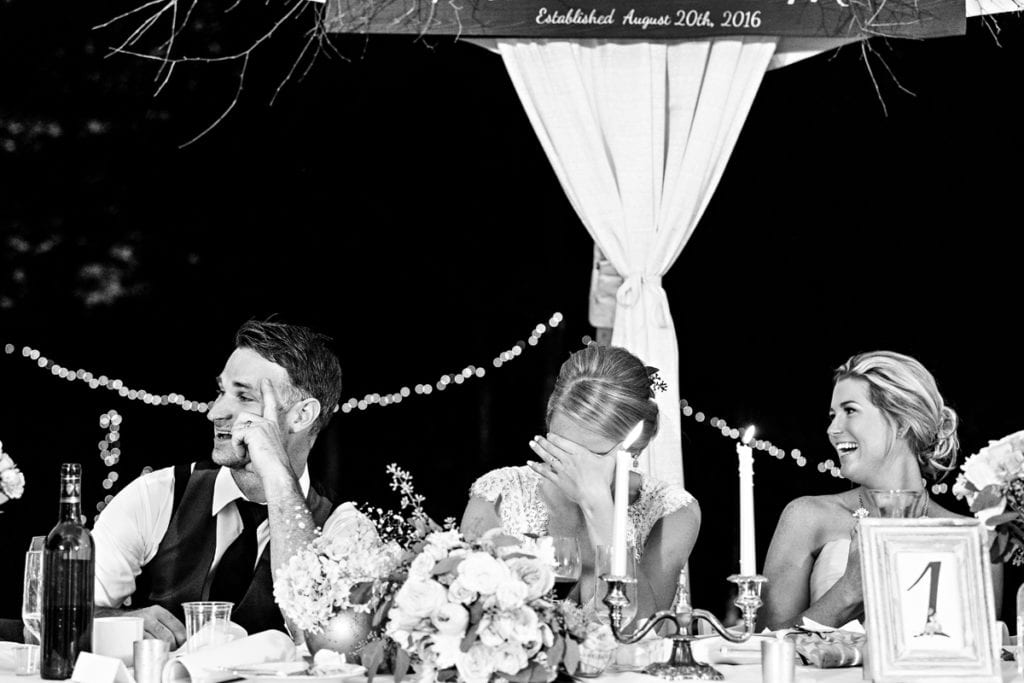 Bride and groom laughing with attendants at head table