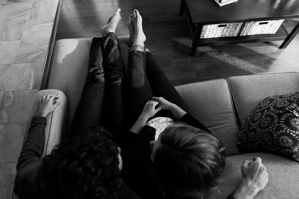 Couple cuddling on couch in modern urban Cornwall engagement session