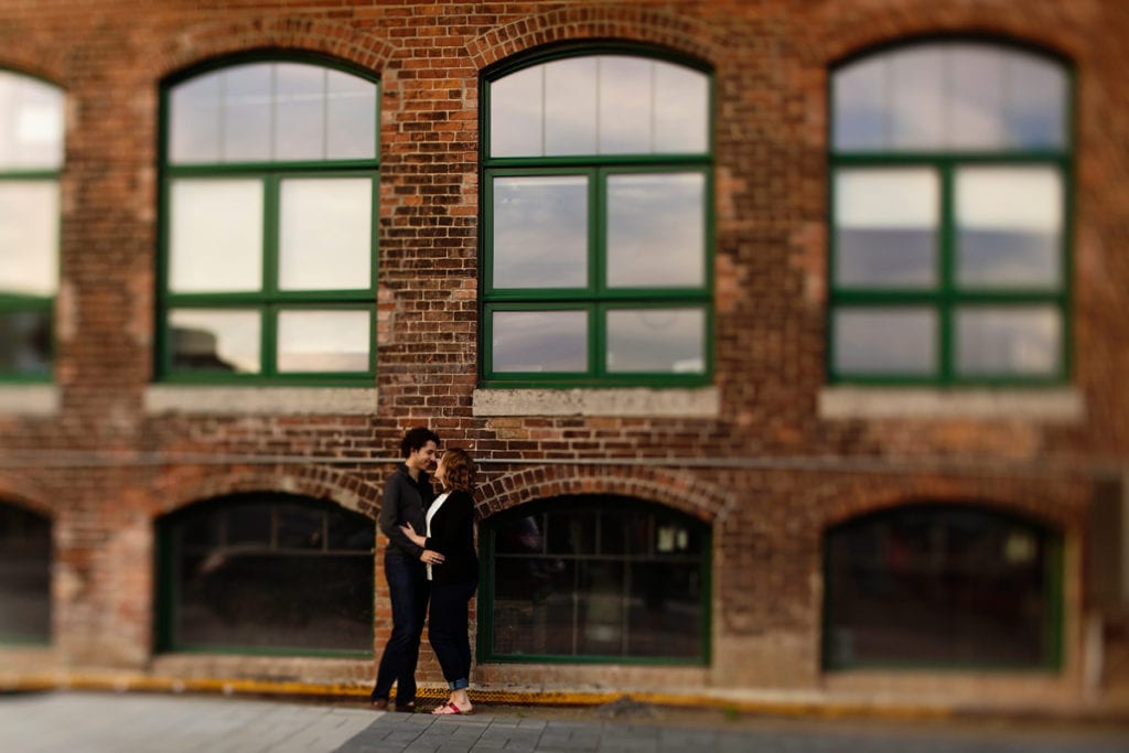 Couple kissing in front of modern industrial loft in urban engagement session
