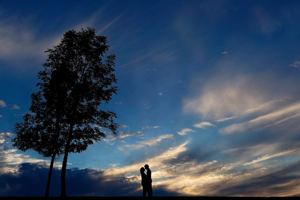 Kissing couple silhouette against blue sky and beautiful clouds