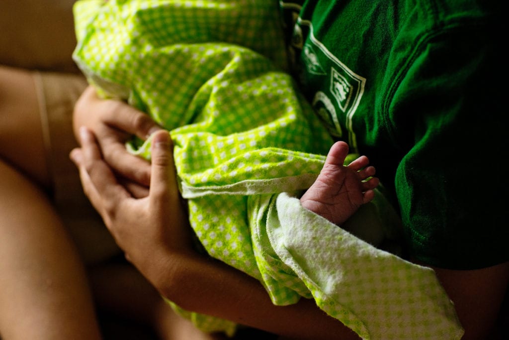 Swaddled newborn baby with foot peeking out