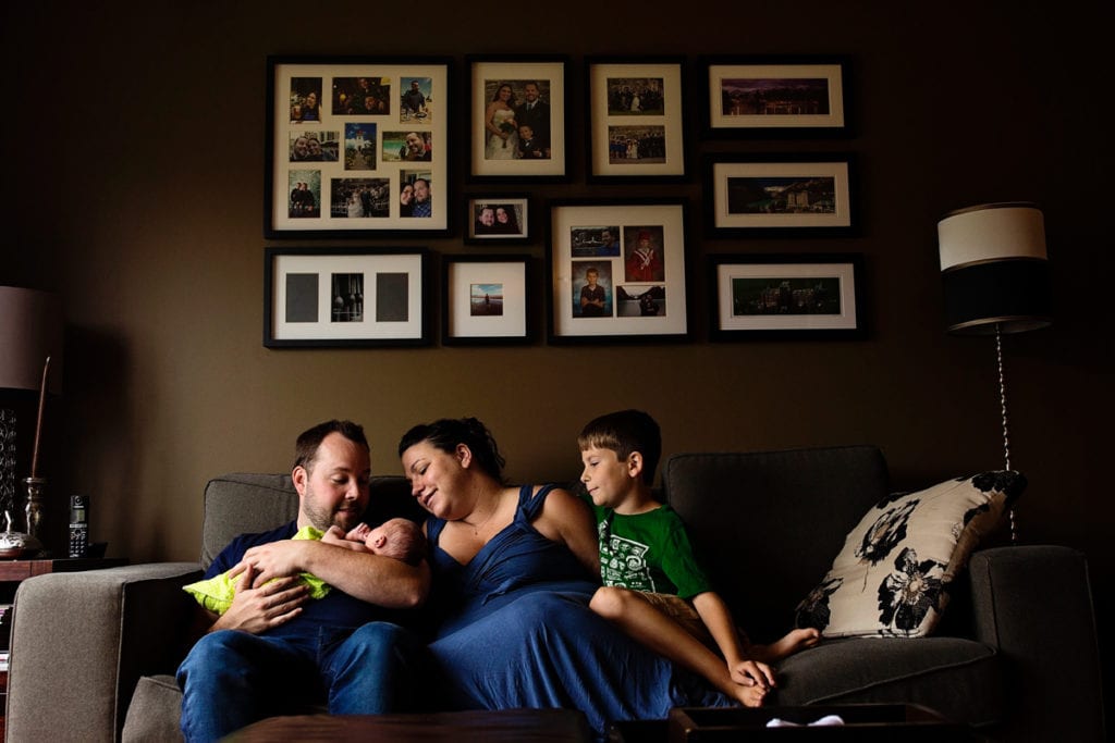 Cornwall family on living room couch under picture frames