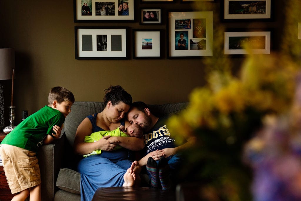 Candid family shot of boy meeting baby brother on living room couch