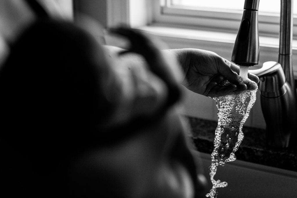 Mom testing bath temperature in kitchen sink