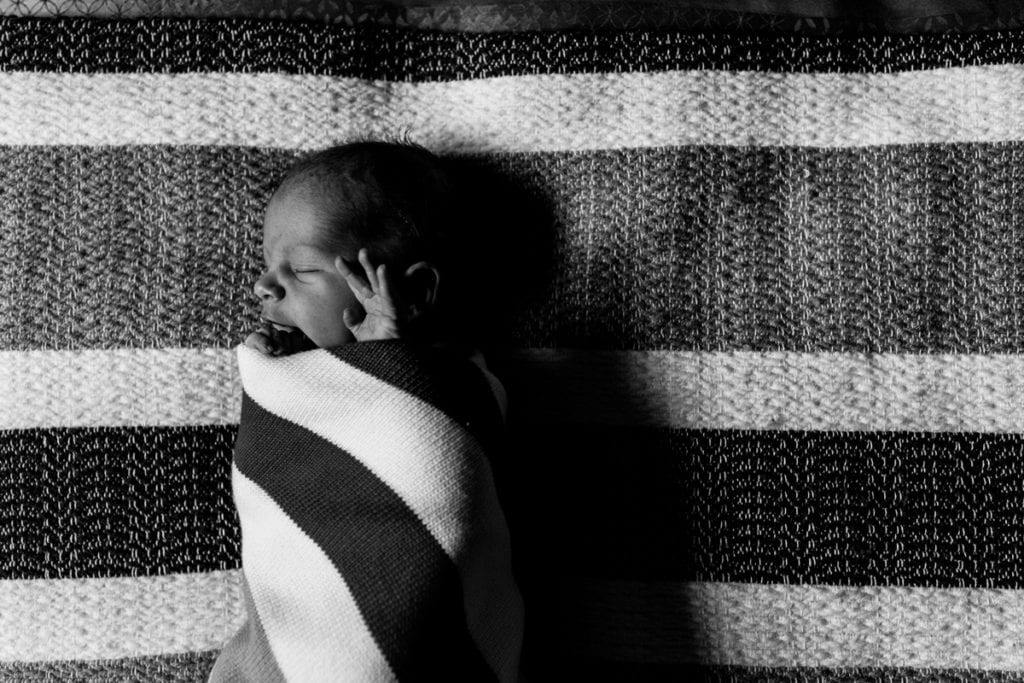 Newborn baby boy in striped swaddle
