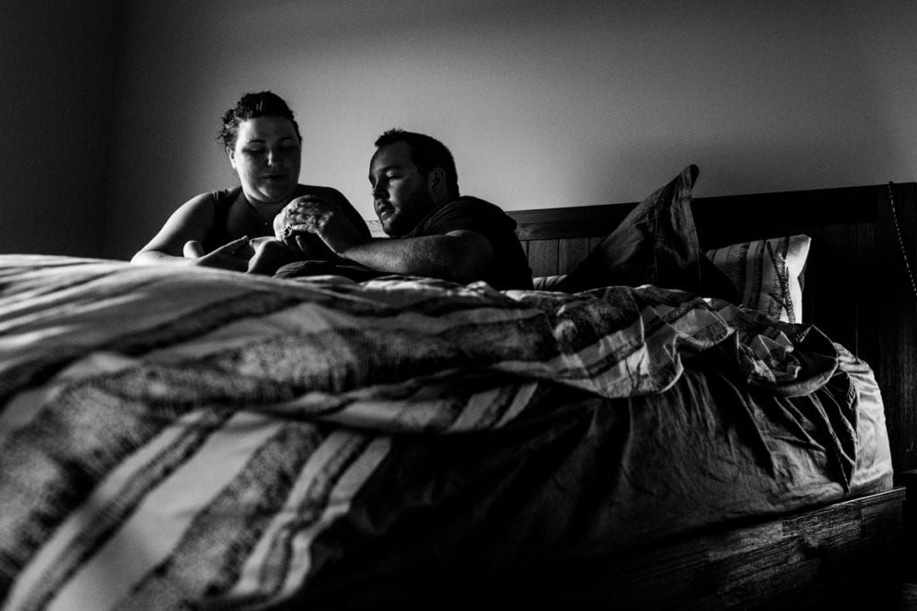 Parents with newborn infant on bed