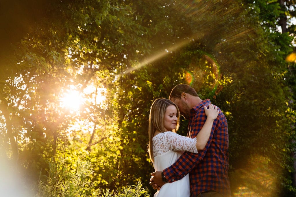 Woman with arm around man's shoulder in sunlit rural Cornwall engagement session