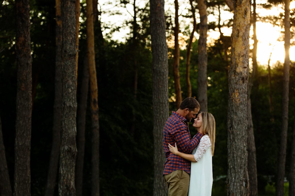 Woman in white dress and fiance in sunset forest engagement shoot