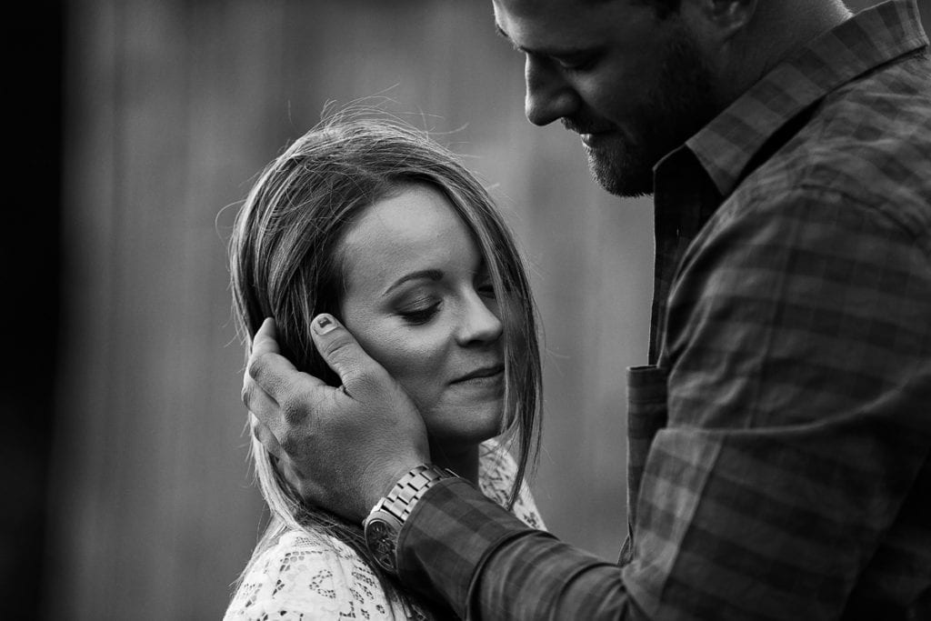 Rugged man holding fiancee's hair back from face