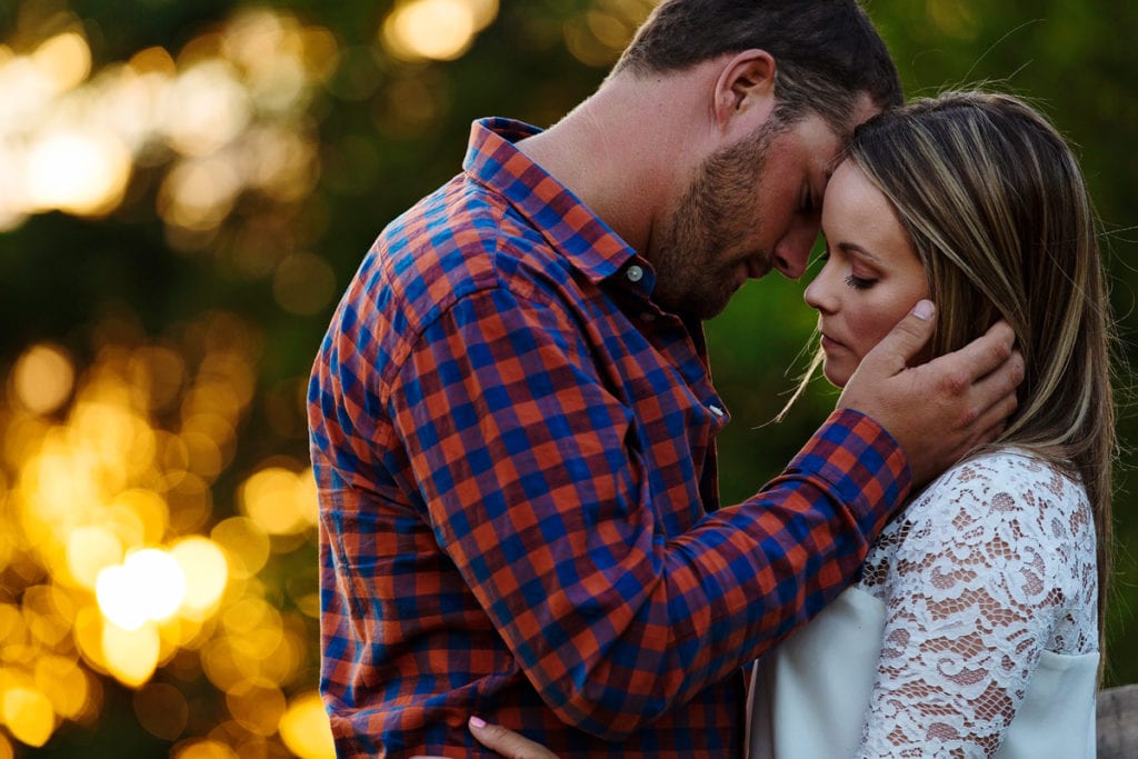 Man in plaid shirt gently holding fiancee's face