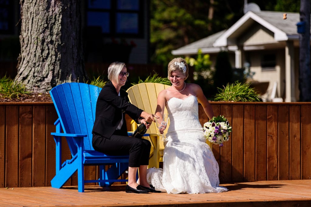 brides toasting with champagne on waterfront dock in chic cornwall wedding