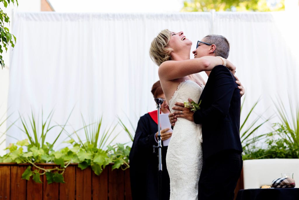 brides laughing at the alter in chic outdoor same-sex wedding