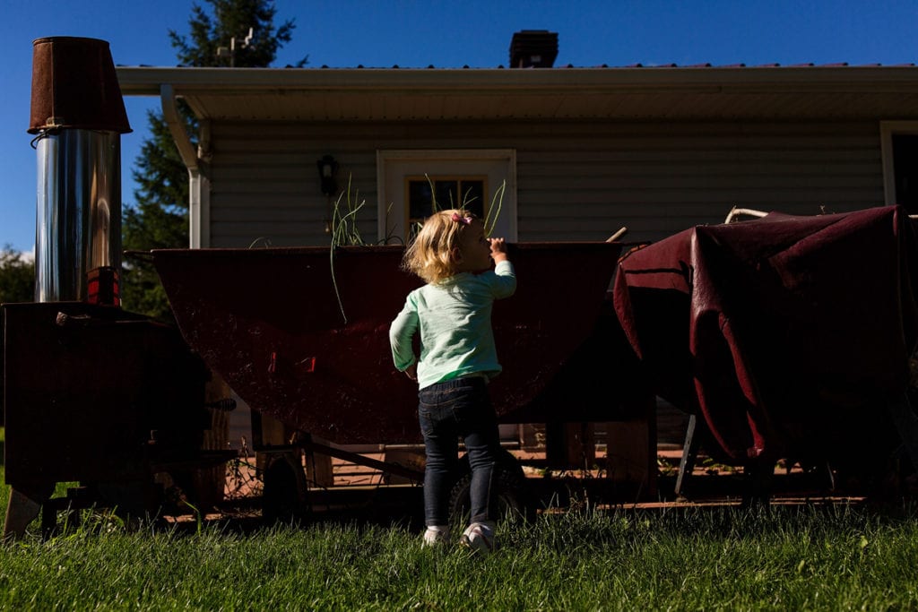 little girl peeking into wheelbarrow in candid Cornwall family session