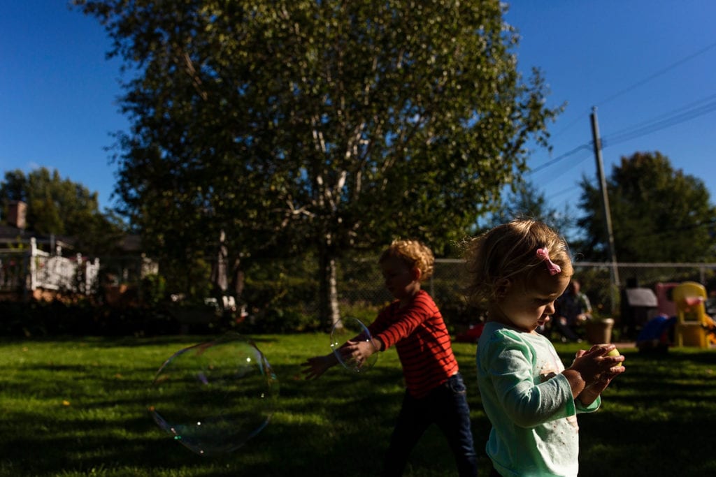 little boy and sister playing with bubbles in backyard