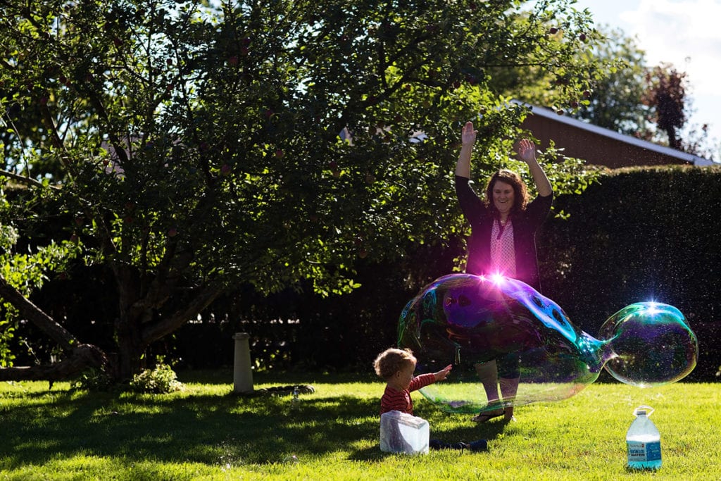 woman making bubbles with little boy in backyard