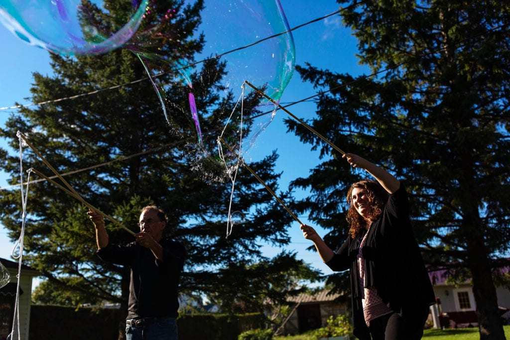 family making soap bubbles with large wands