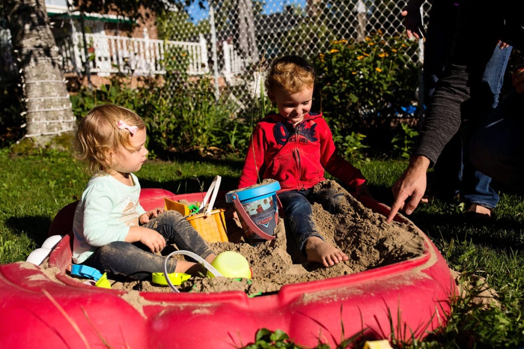 brother and sister playing in sandbox in candid backyard family session