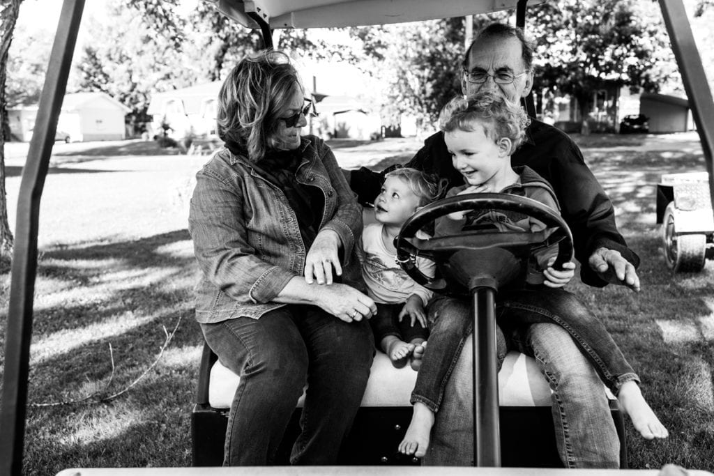 grandparents and grandchildren driving golf cart