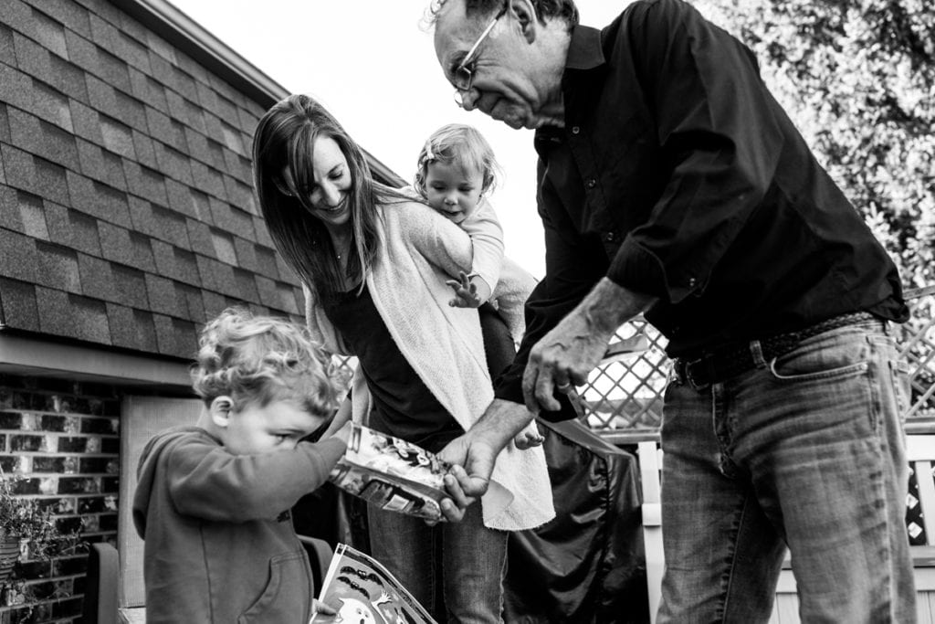 grandfather giving grandson a snack and mom piggybacking daughter