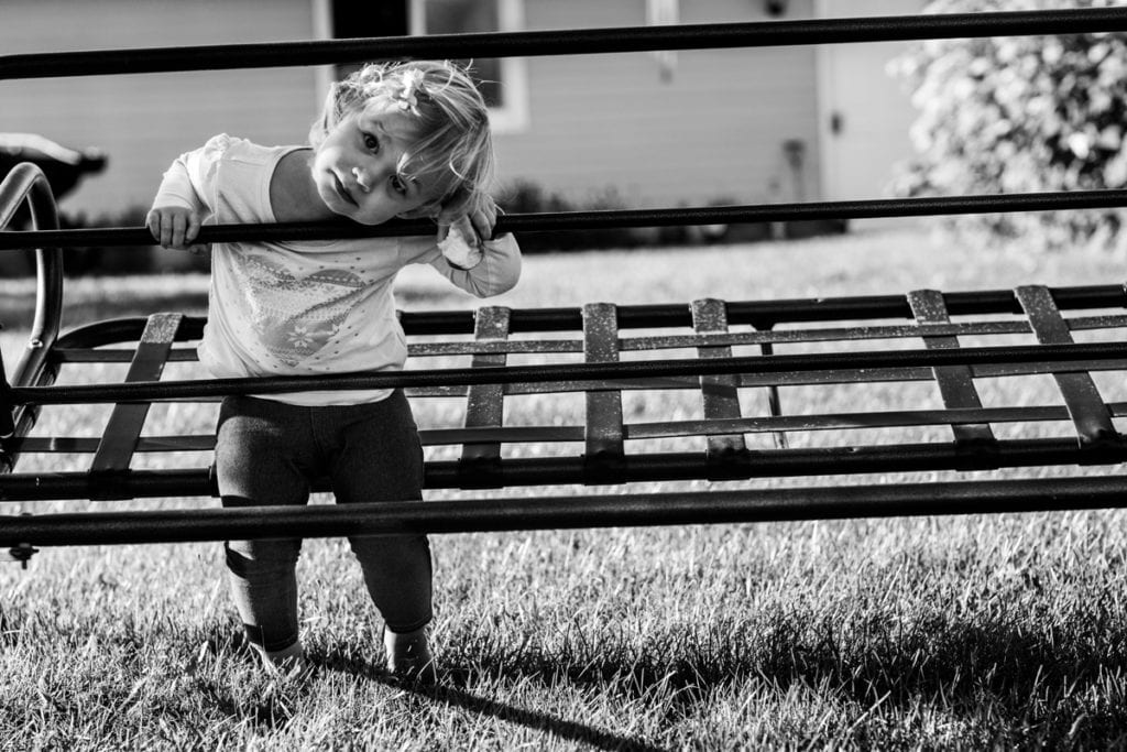 Little girl peeking through swing bars
