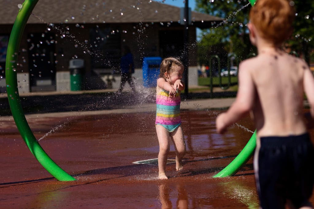 brother spraying sister with water at splash park