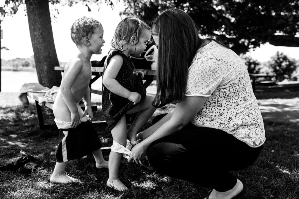 mom quick changing kids in the park to play at splash pad