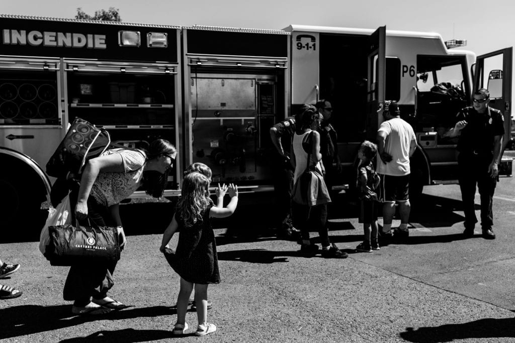 little boy and girl waving at firefighters beside fire truck