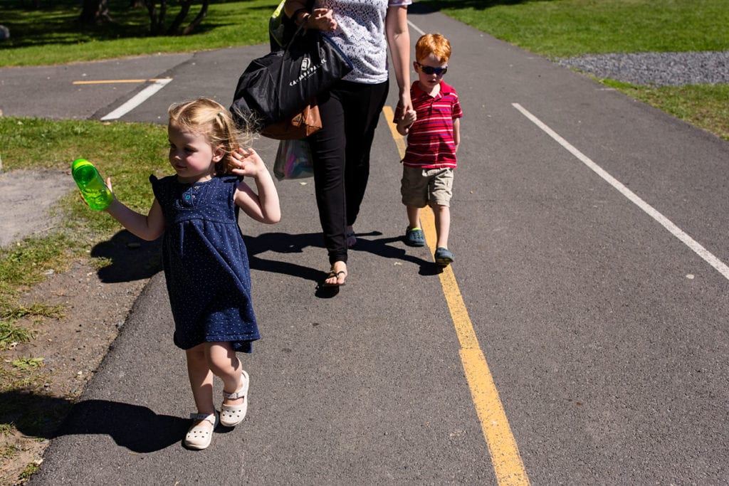 mom with son and daughter walking on path in summer sun
