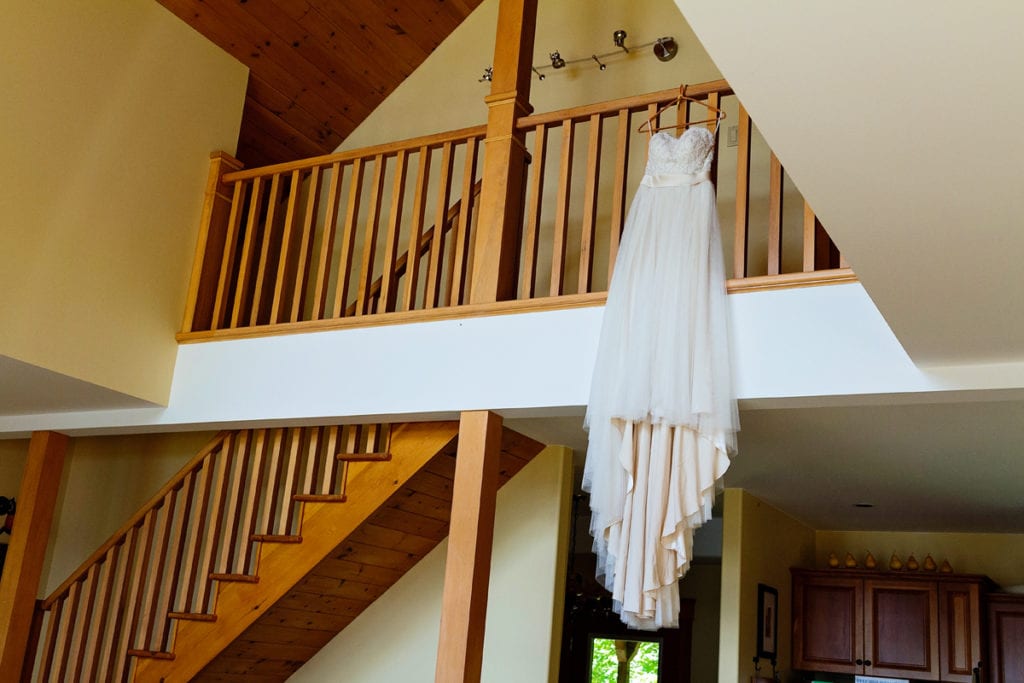 wedding dress hanging from balcony in rustic log cabin at Calabogie lake wedding