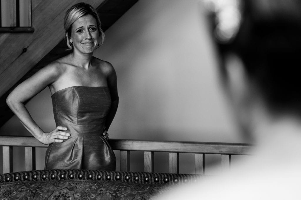 bridemaid looks on as bride gets ready before ceremony