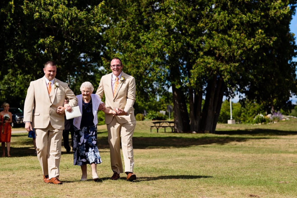 groom and best man helping grandmother to wedding ceremony