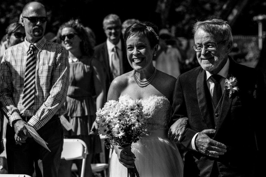 smiling bride being walked down the aisle by her father
