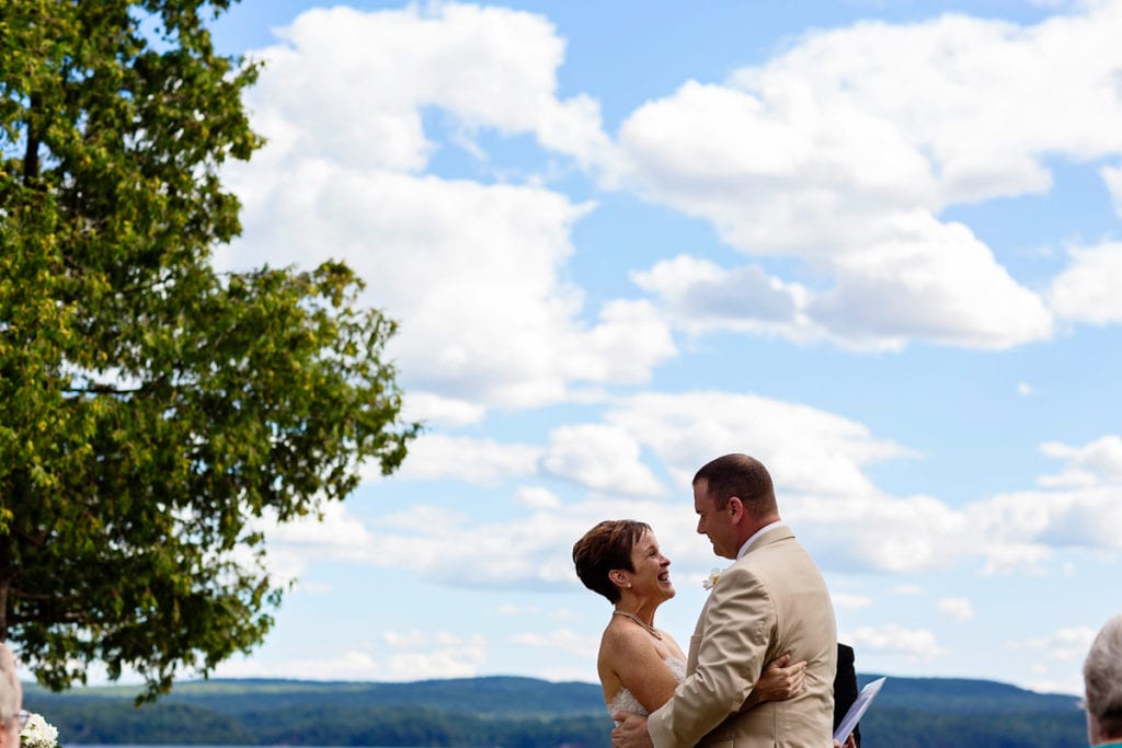 bride smiling enthusiastically during vows at lakeside wedding