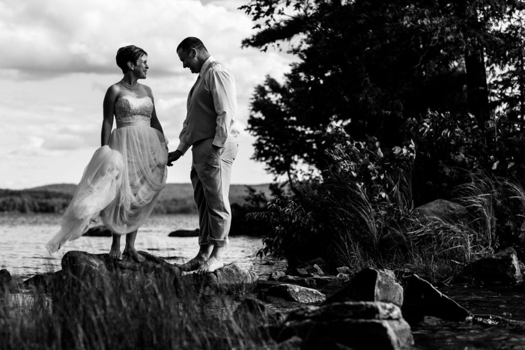 barefoot bride and groom holding hands perched on rocks in Calabogie wedding