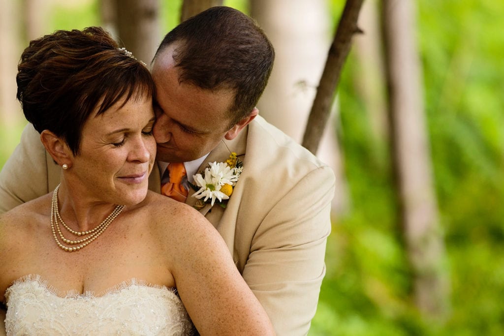 Groom kissing bride's cheek at summer Calabogie wedding