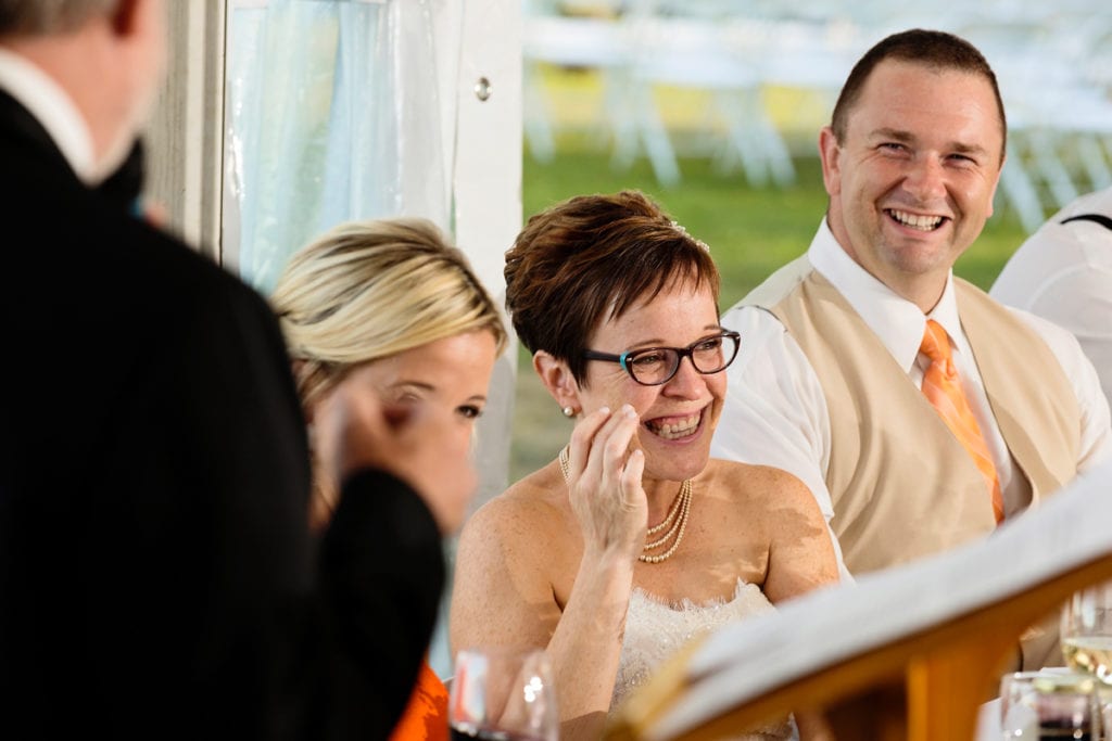 bride and groom laughing during speeches at intimate lakeside wedding