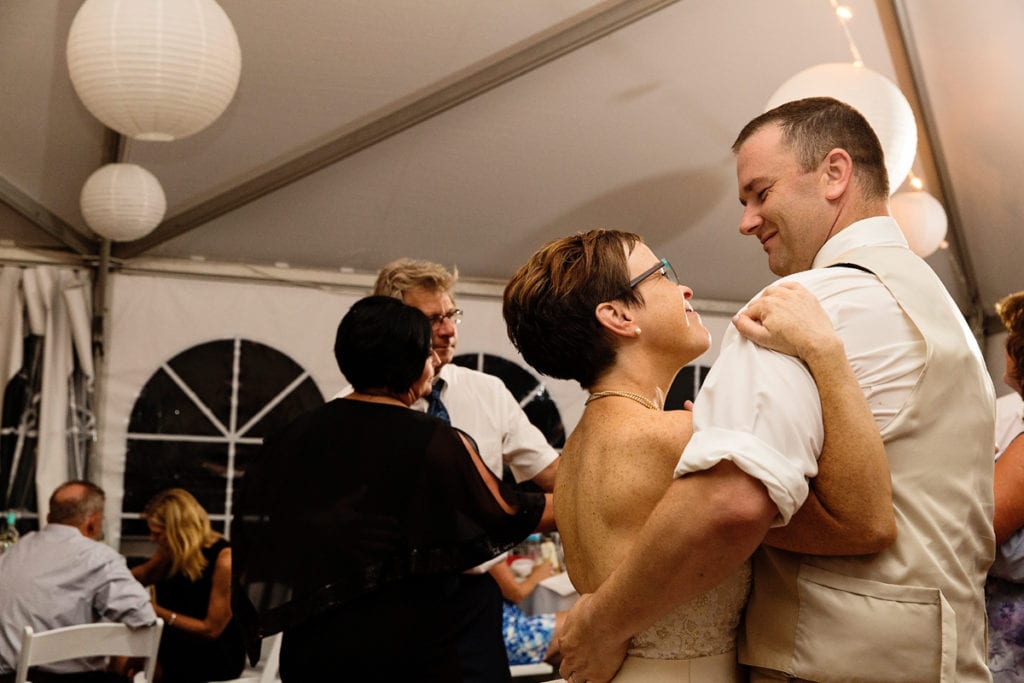 bride and groom dance amongst guests at tented lakeside wedding reception