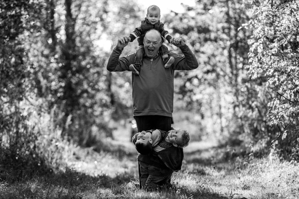 little kids hanging off grandpa giving shoulder ride on nature trail