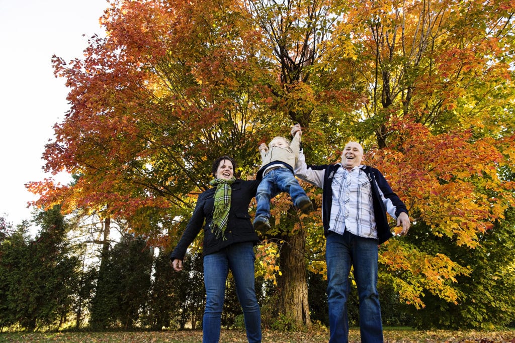 mom and dad swinging little boy in rural fall photo shoot